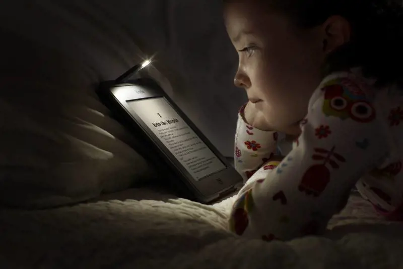 Una bimba legge il tablet nel letto