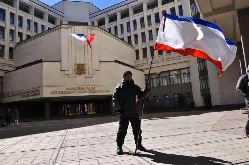 Miliziano con la bandiera russa davanti al parlamento della Crimea