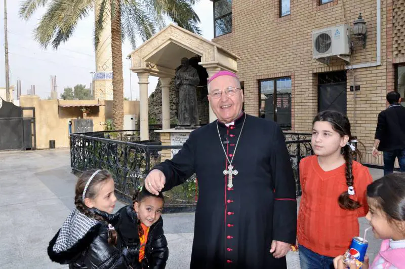 Monsignor Shlemon Warduni nella parrocchia del Sacro cuore di Baghdad con la statua di padre Pio sullo sfondo 