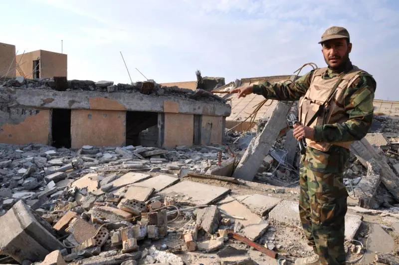 Soldato iracheno a Tikrit indica la tomba mausoleo di Saddam Hussein distrutta dai combattimenti 