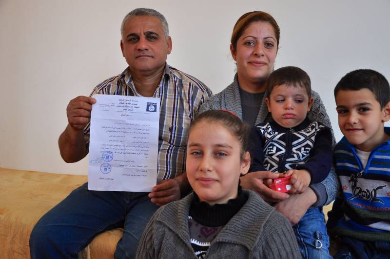 La famiglia al completo con il documento del Califfato sula conversione (forzata) dei cristiani con i nuovi nomi musulmani dei tre figli della coppia cristiana