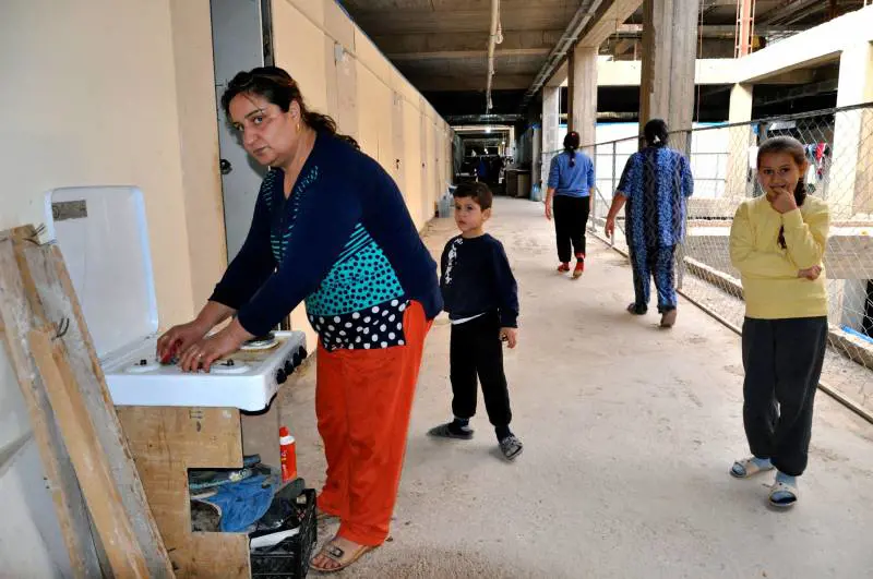 Rifugiata cristiana pulisce un fornello nel centro ricavato in un super magazzino di Ainkawa in costruzione ad Erbil in Kurdistan 