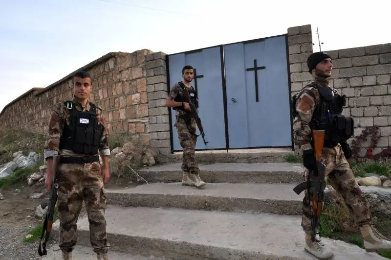 Volontari assiri dvanti al cimitero cristiani