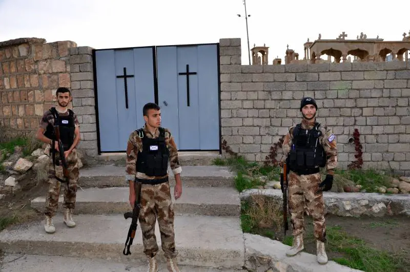 Volontari assiri dvanti al cimitero cristiani
