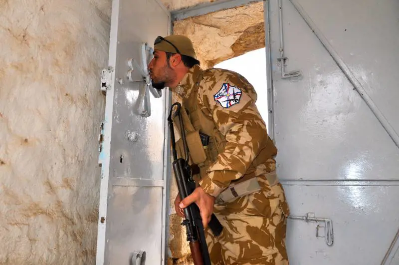Volontario cristiano bacia la croce all'ingresso della chiesa di San Giorgio nel villaggio abbandonato di Bakufa a nord di Mosul