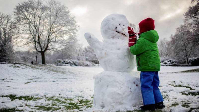 Un bambino costruisce un pupazzo di neve a Berlino