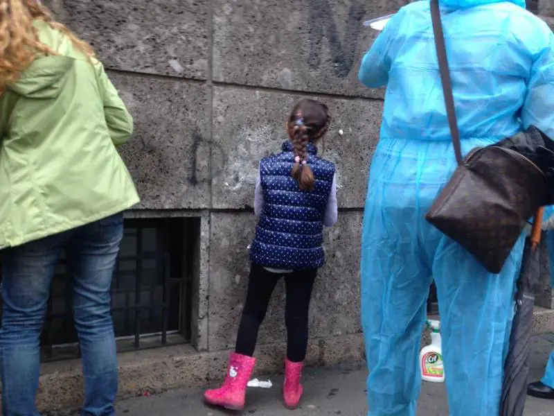 Una bimba ripulisce le scritte dei black bloc dalle vie di Milano