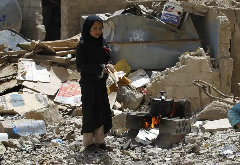A Sanaa una ragazzina cucina su un fuoco improvvisato tra le macerie