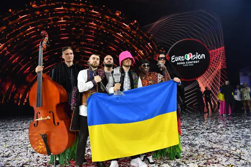 I cantanti già armi in pugno. Gli auguri di Zelensky e Nato. Le bombe russe con le strofe