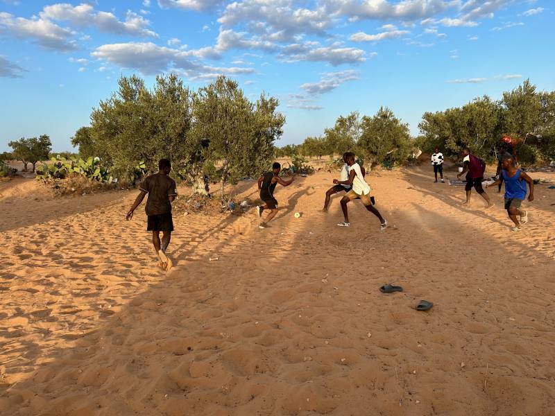 I migranti giocano a calcio nel bivacco alla periferia di El Amra in attesa della partenza per l'Italia.