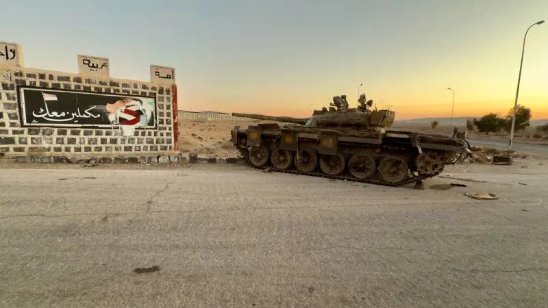Carro armato abbandonato davanti a un murales pro Assad
