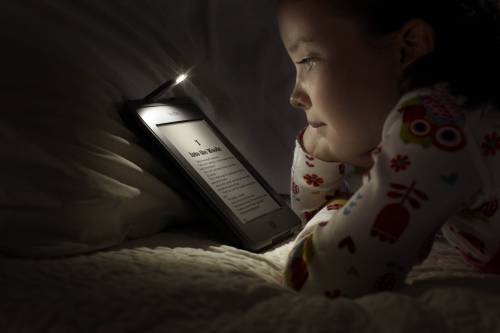 Una bimba legge il tablet nel letto