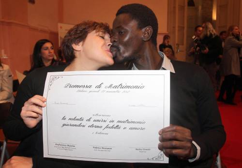 Una coppia si scambia un bacio mostrando la "promessa di matrimonio delle coppie di fatto"