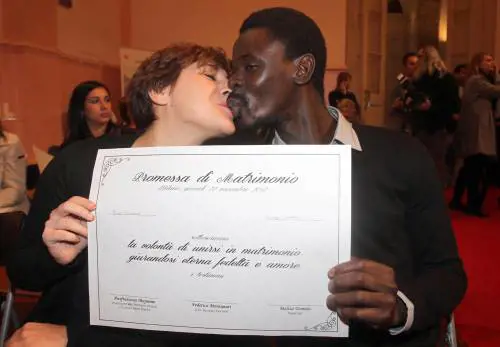 Una coppia si scambia un bacio mostrando la "promessa di matrimonio delle coppie di fatto"