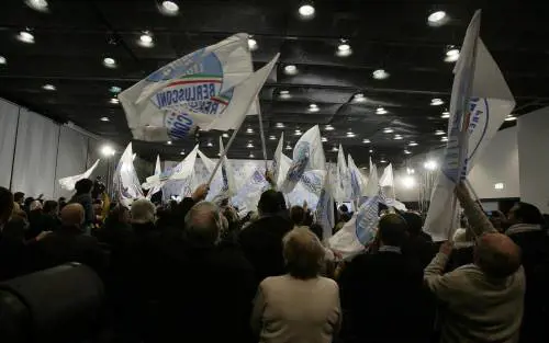 Il pubblico sventola le bandiere all'ingresso di Silvio Berlusconi