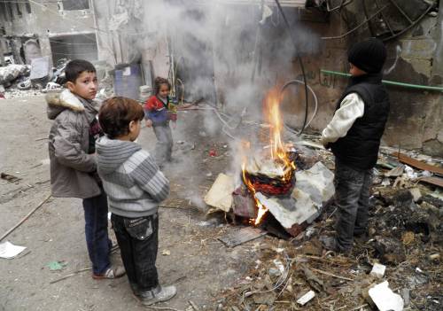 Bambini di Homs si scaldano intorno a un fuoco nella città assediata