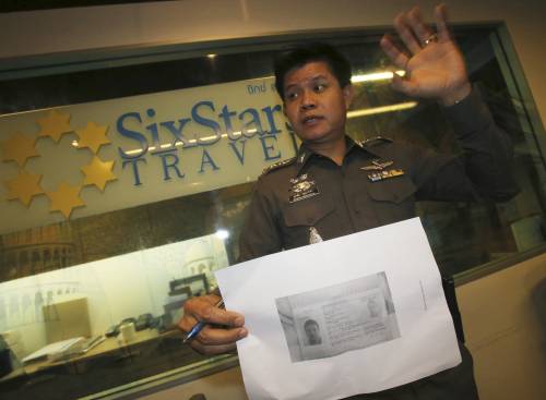 Un poliziotto thailandese con la foto del passaporto rubato a Luigi Maraldi