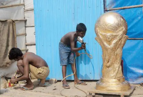 Ragazzi si improvvisano artisti per guadagnare qualcosa e colorano una riproduzione della coppa del mondo