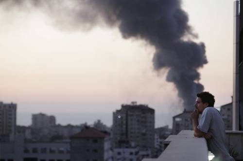 Il videoreporter italiano Simone Camilli. Sullo sfondo, fumo sale dopo un attacco israeliano
