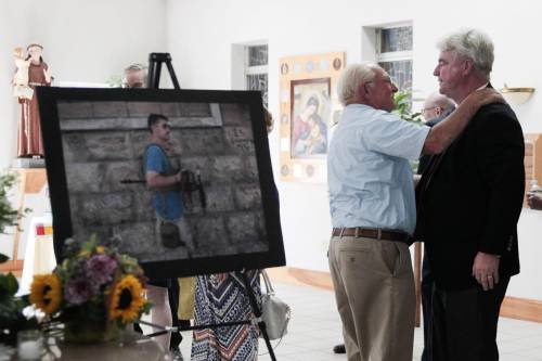 Il padre di Foley durante una commemorazione; accanto, la foto del figlio
