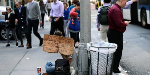 Un giovane con un cartello che dice: "Senzatetto 23enne affamato e senza famiglia chiede aiuto e cerca una stanza"