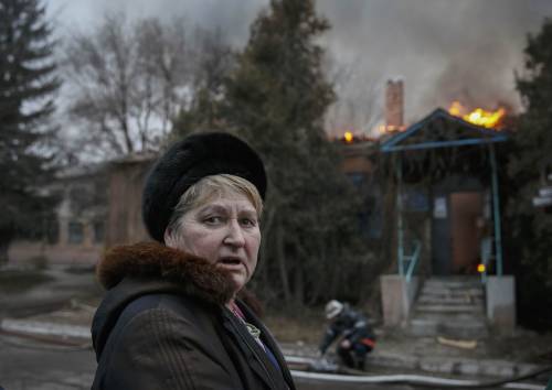 Un abitante di Artemivsk, nell'Ucraina orientale, davanti a un edificio in fiamme