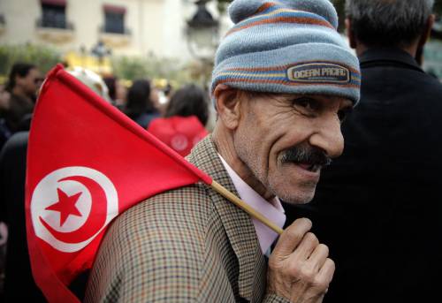 Un manifestante tunisino; sulla spalla, la bandiera del Paese