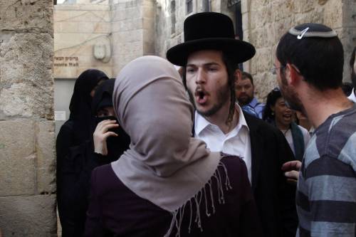 Un ebreo ultra-ortodosso discute con una donna musulmana nella Città vecchia