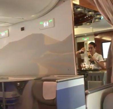 L'hostess del volo Emirates versa lo champagne avanzato in una bottiglia
