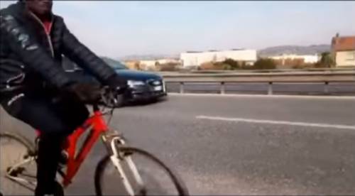 Migrante sulla bicicletta ​pedala in superstrada