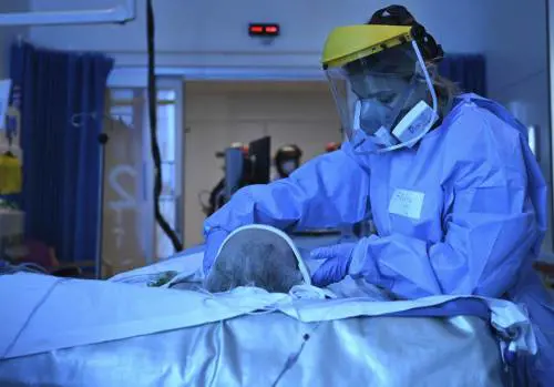 Un medico indossa i dispositivi di sicurezza per trattare il paziente (LaPresse)