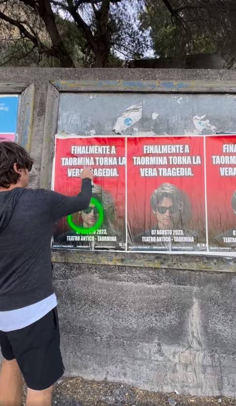 Il comico Angelo Duro mentre imbratta uno dei manifesti del suo spettacolo a Taormina