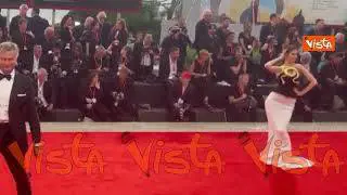 Venezia 82, una modella sfila sul red carpet con un abito decorato da un serpente dorato