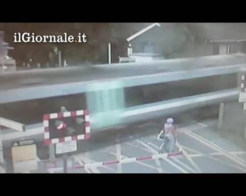 Ciclista attraversa passaggio a livello mentre passa il treno