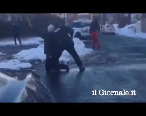 I bimbi giocano con le palle di neve. L'agente di polizia sfodera la pistola