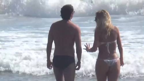 Valeria Marini sexy in spiaggia con micro bikini bianco: tuffo con l'amico e selfie coi fan