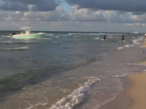 Florida, modella posa sulla spiaggia: alle sue spalle sbarcano gli immigrati