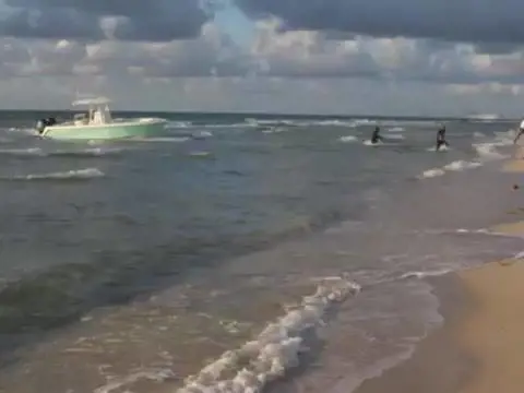 Florida, modella posa sulla spiaggia: alle sue spalle sbarcano gli immigrati