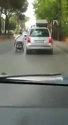 Il disabile in carrozzina trainato da una vettura in strada