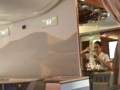L'hostess del volo Emirates versa lo champagne avanzato in una bottiglia