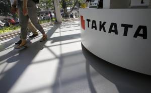 Visitatori di uno showroom a Tokyo passano accanto a uno stand Takata