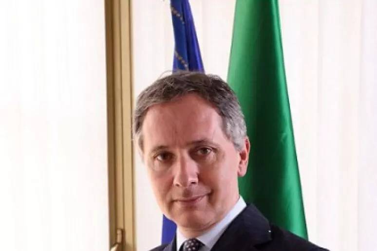 Uomo in abito scuro in ambiente istituzionale durante cerimonia ufficiale