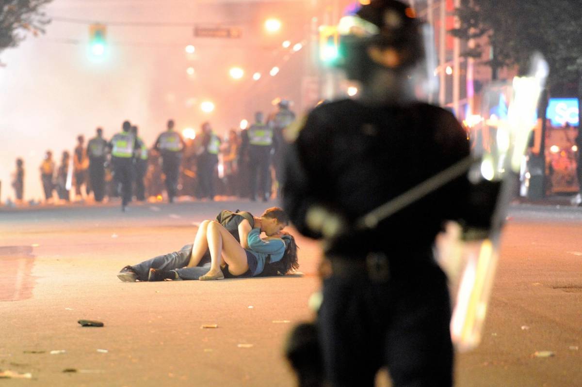 Si baciano mentre intorno 
scoppia la guerriglia 
La foto fa il giro del web