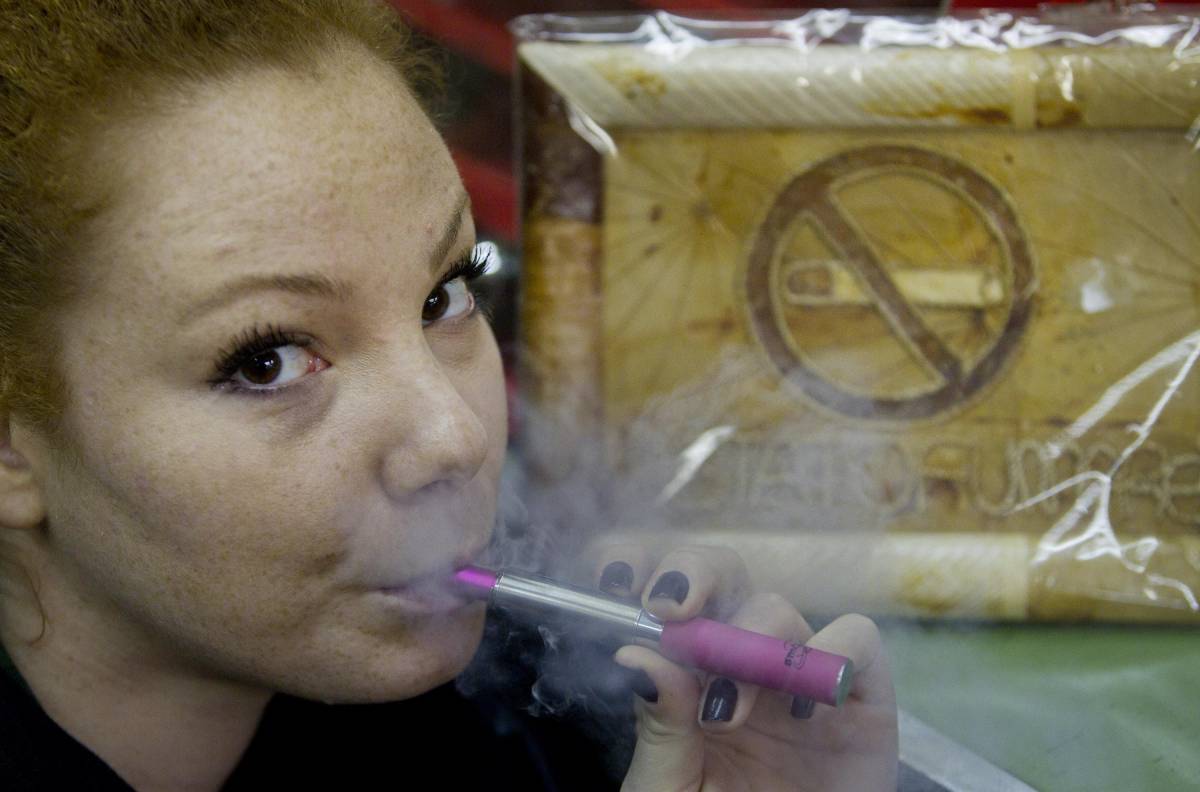 Una ragazza fuma una sigaretta elettronica in un locale pubblico