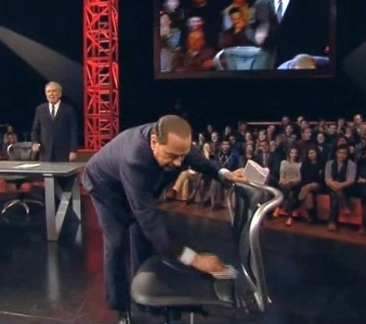 Silvio Berlusconi mentre pulisce la sedia dove era stato seduto Marco Travaglio