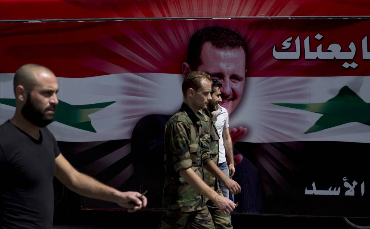 Soldati accanto a un bus con il volto del presidente Assad a Damasco