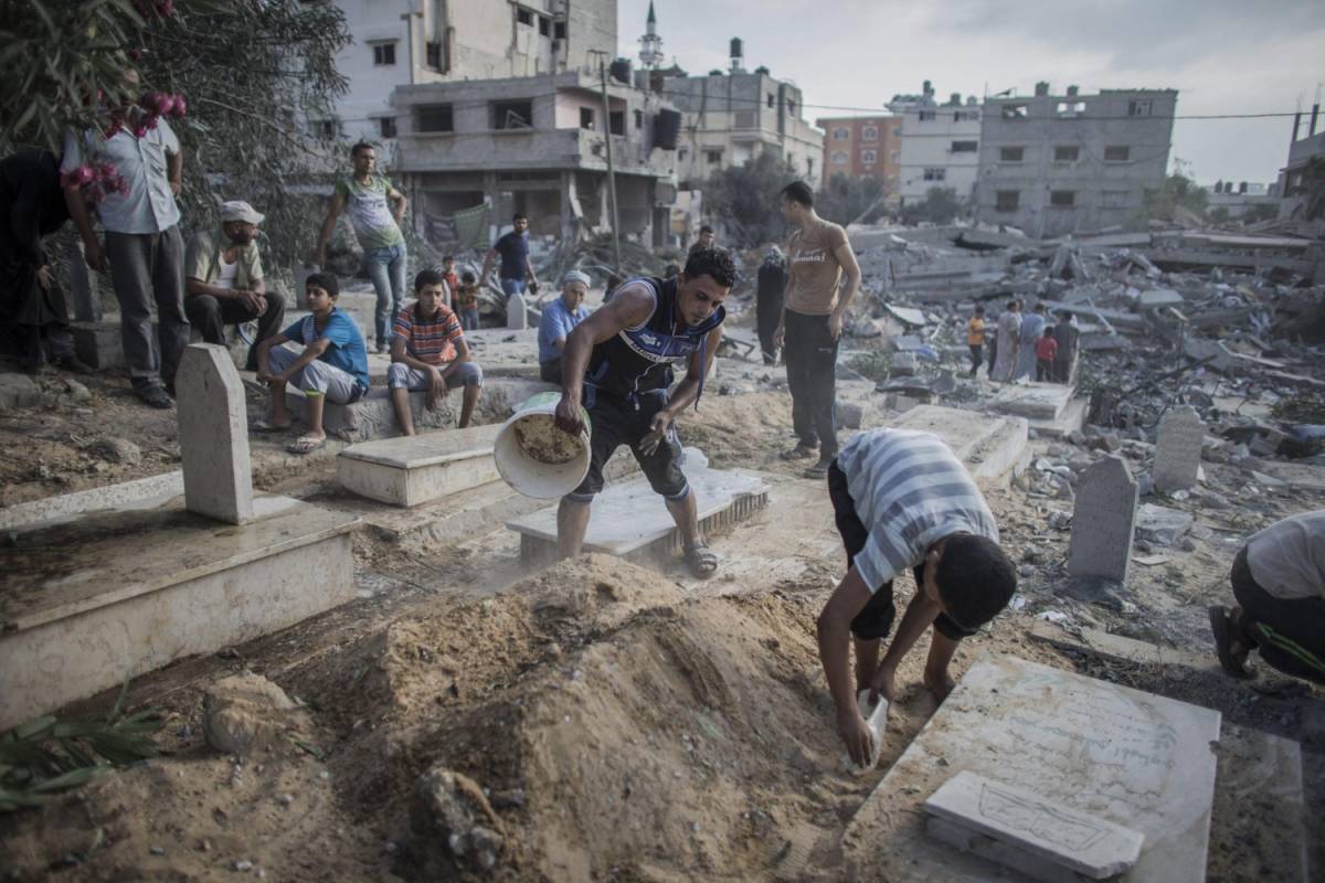 Gaza, uomini al lavoro per ripulire alcune tombe dalle macerie