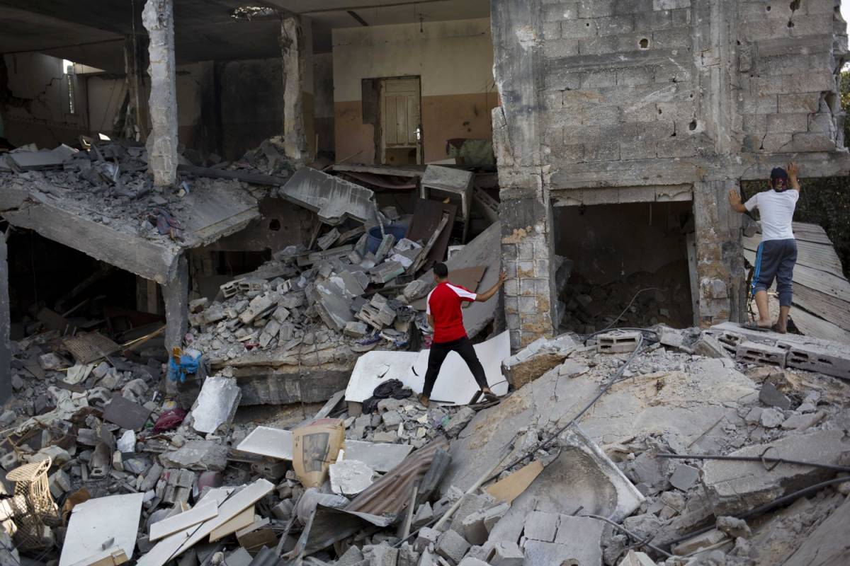 Palestinesi tra i resti di una casa distrutta nella città di Gaza