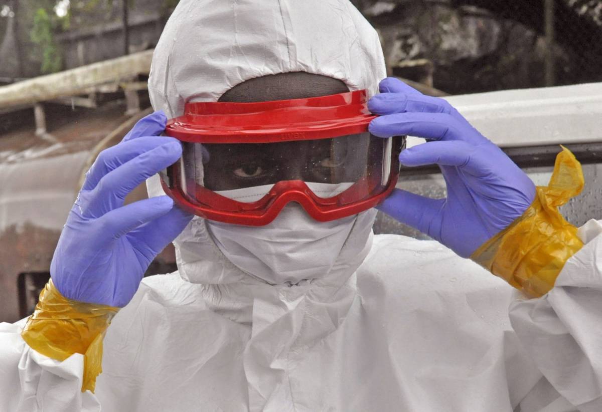 Un operatore sanitario liberiano si prepara a spostare il corpo di un uomo morto d'ebola