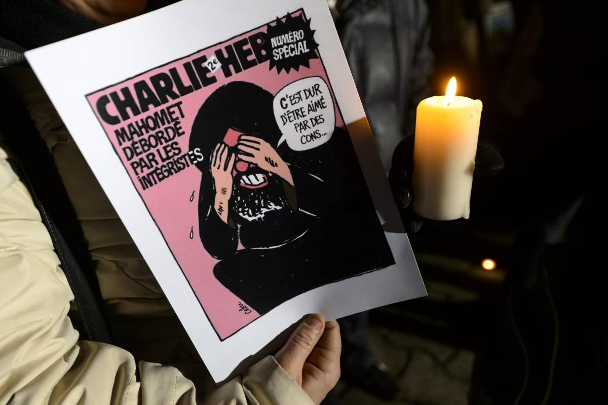 Un manifestante con una vignetta di Charlie Hebdo a Losanna